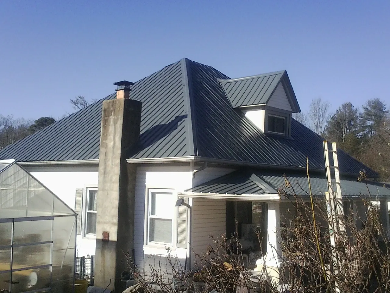 Dark blue standing seam metal roof on a white farmhouse with dormer — Slate & Tile Roof Repair by Roofing Brothers in Accord
