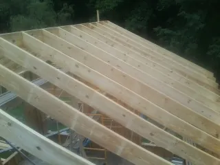New roof rafters set over an addition before sheathing in Accord