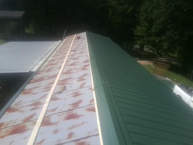 Old rusted panels beside newly installed green metal roofing — Wind Damage Roof Repair by Roofing Brothers in Accord