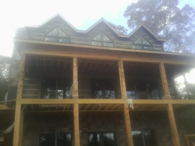Dormers and porch framing on a large log home under construction — Roof Coating work by our crew in Accord