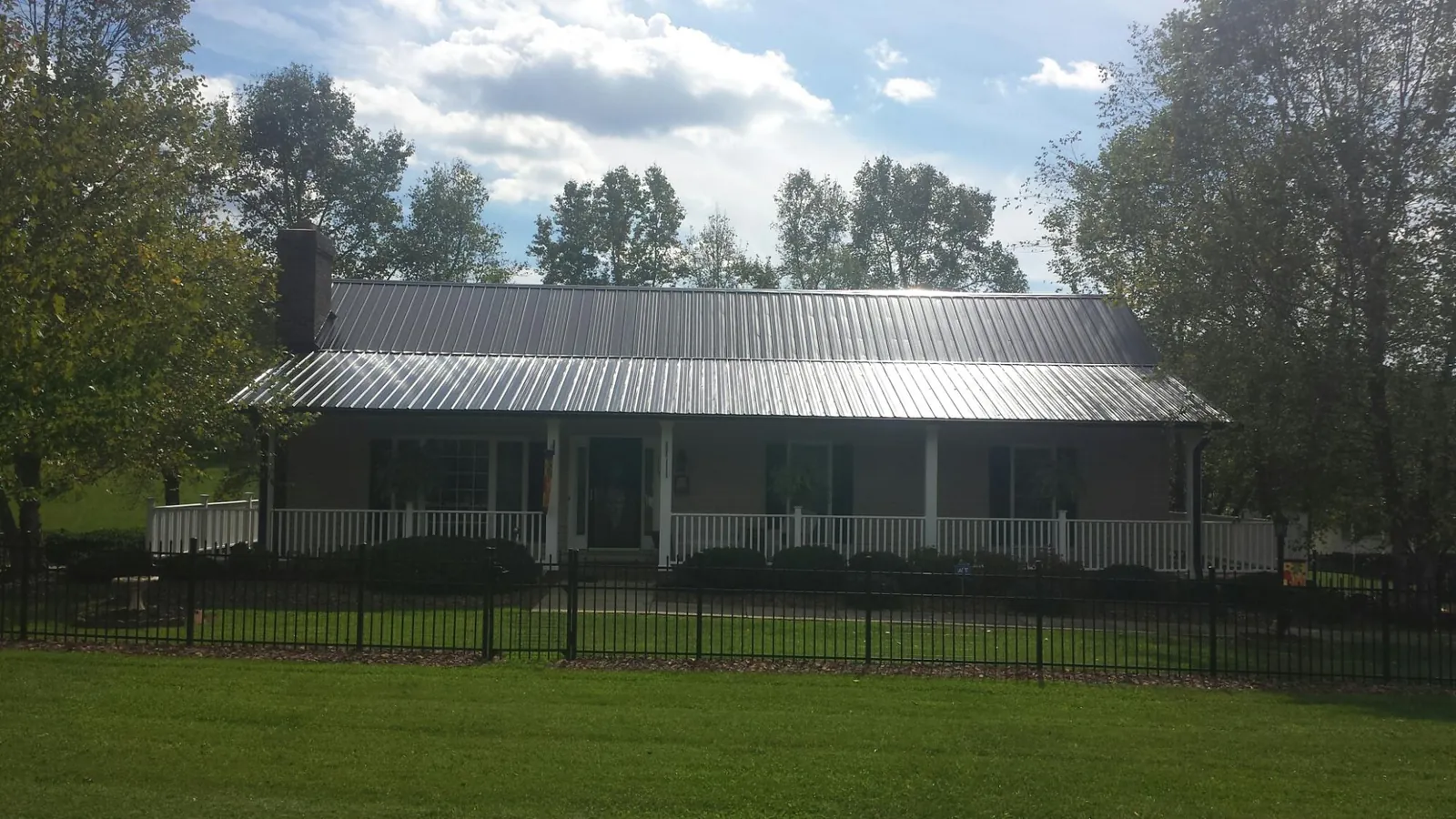 Gray metal roof on a brick ranch with a full width front porch — Gutter Guard Installation work by our crew in Accord
