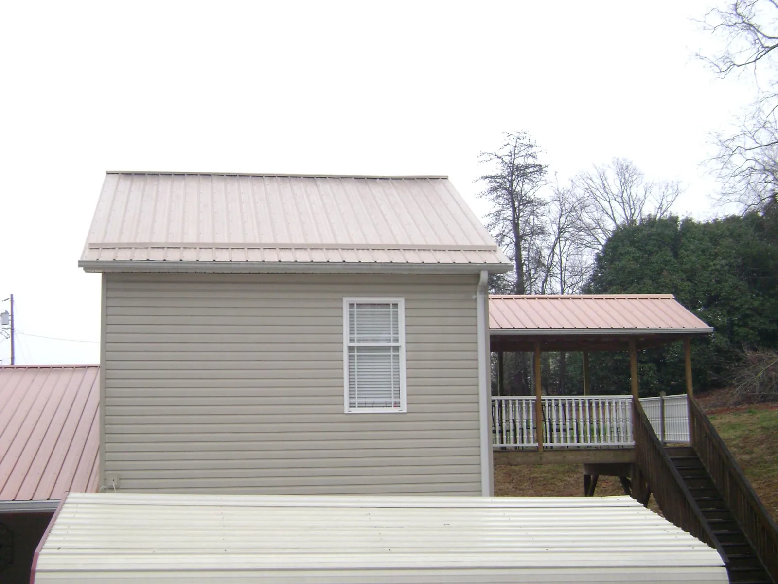 Tan metal roofs on a two story addition and attached porch, from a Roof Replacement job in Accord