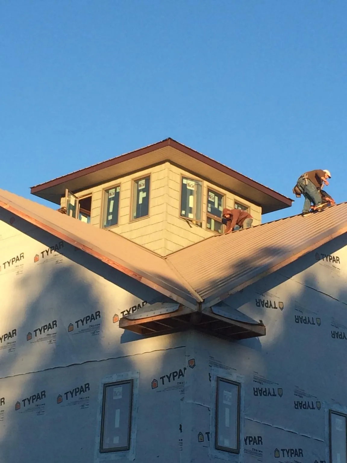 Roofers working around a rooftop cupola on a new metal roof at sunset — Roof Waterproofing in Accord by Roofing Brothers